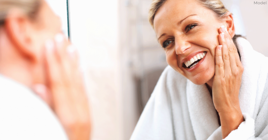 Woman looking in the mirror, smiling.