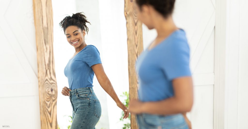 Woman in Ann Arbor admiring tummy tuck results in mirror