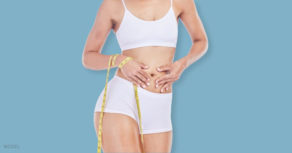 Woman in white undergarments standing with tape measure in hand. (MODEL)