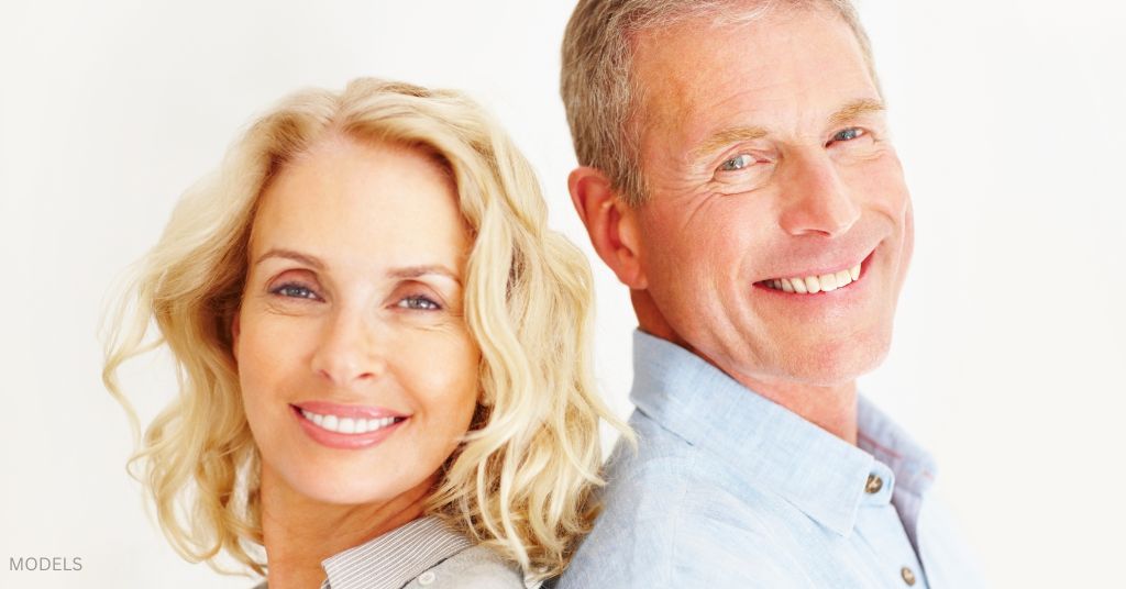 Mature man and woman smiling back to back. (MODELS)